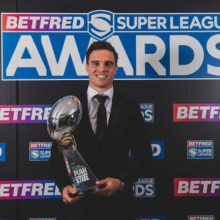 Brodie Croft in a suit holding the 2022 Man of Steel trophy at the Betfred Super League Awards